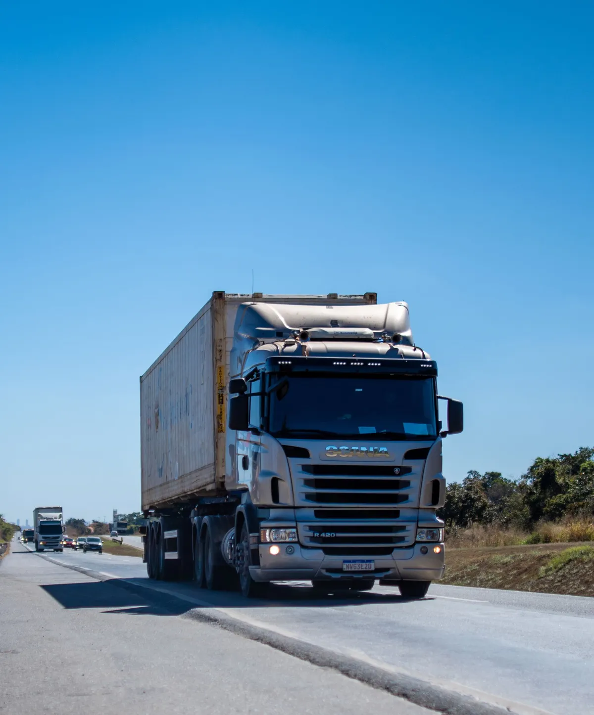 Tractocamión transportando un contenedor marítimo por una carretera de doble calzada.